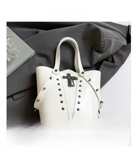 Detail view of white bucket bag with black punk studs and metal cross embellishment
