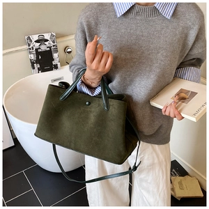 Detailed shot of dark green suede tote bag with leather straps and snap closure