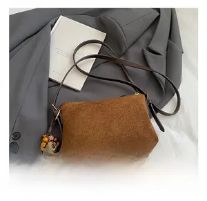Detalle del bolso bandolera de ante marrón mate con colgantes de flecos de cuentas coloridas