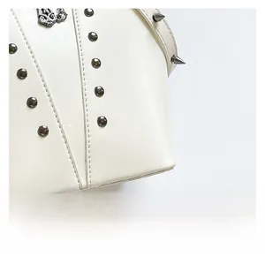 Macro detail of white leather crossbody bag with silver studs and metal spikes