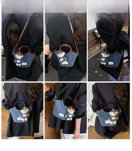 Dettaglio della borsa a secchiello in denim con manico in pelle e ciondolo a forma di orso