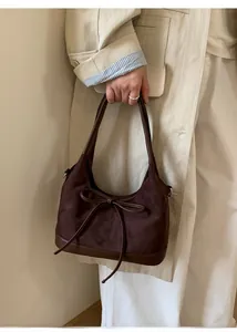Detail of vintage brown suede tote bag with leather piping and decorative bow tie detail