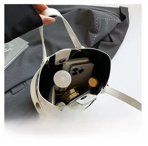 Spacious interior of white glossy bucket bag showing phone, lipstick and magnetic closure