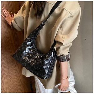 Detailaufnahme einer schwarzen geflochtenen Hobo-Tasche mit glänzender Textur am Modell