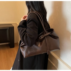 Détail du sac cabas en cuir marron foncé avec boucle métallique et bandoulière de mode