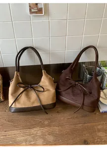 Detail of suede tote bags with leather trim and decorative bow in tan and brown