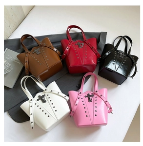 Flat lay of retro studded tote bags in multiple colors featuring metal cross charms