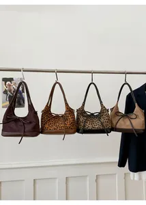 Detail view of four shoulder bags in leopard print and suede with elegant bow accents