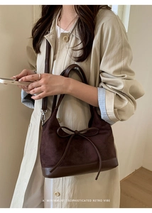 Close-up of brown suede and leather tote bag featuring a decorative bow tie detail