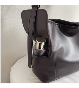 Détail de la poche latérale d'un sac cabas marron montrant la capacité de rangement