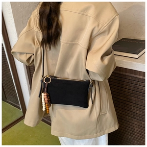 Detalle de bolso bandolera negro mate con borla de cuentas étnicas y cremallera dorada