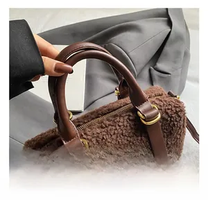 Détail du sac à main en peluche marron montrant la poignée en cuir et métal doré