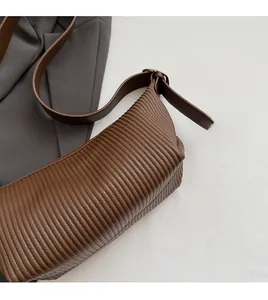 Detailed view of dark brown faux leather shoulder bag with horizontal pleated texture
