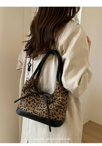 Detail of leopard print tote bag with a leather bow and trim shown on a model