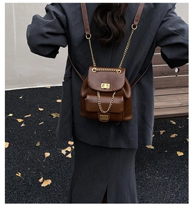 Detail eines braunen Vintage-Stepprucksacks mit goldenen Drehverschlüssen und Kettengurten