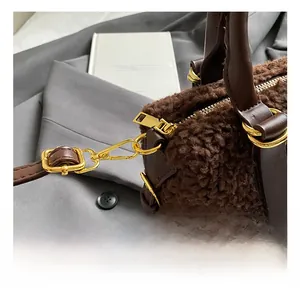 Détail des crochets en métal doré et de la bandoulière en cuir brun sur le sac en peluche