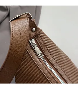 Close-up of brown litchi leather texture with smooth silver zipper and metal buckle