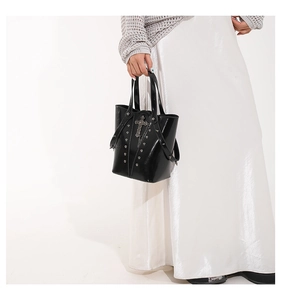Detail of glossy black bucket bag with silver studs and a gothic cross pendant
