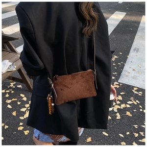 Bolso bandolera de ante marrón con borlas de cuentas sobre el hombro de una modelo