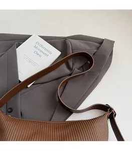 Detail of slim brown leather strap and pleated texture on a vintage baguette shoulder bag