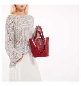 Macro detail of red bucket bag with silver metal cross pendant and rivet studs