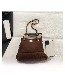 Détail d'un sac seau en daim marron avec franges, motif matelassé et chaîne dorée