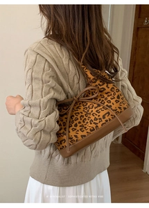 Detail of leopard print tote bag with leather bottom and decorative bow on knit sweater