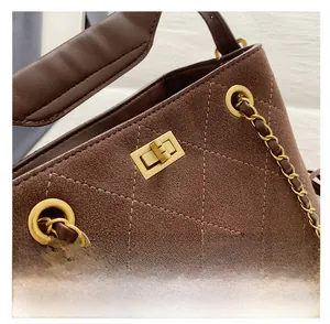 Gros plan du sac seau rétro en daim marron avec surpiqûres et fermoir doré rotatif