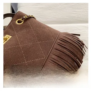 Gros plan des surpiqûres en losanges et des franges sur un sac seau vintage en daim marron