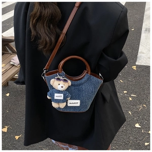 Détail du sac seau en jean bleu avec poignées en cuir marron et breloque ourson mignon