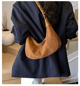 Sac demi-lune marron en daim porté par un mannequin en blazer bleu marine