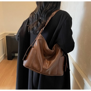 Brown leather tote bag shown on a model highlighting its large size and slouchy texture