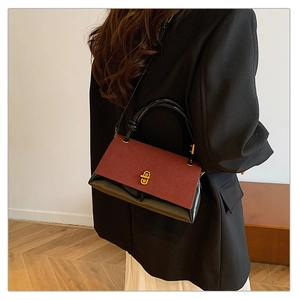 Detail showing red-brown suede and black leather bag with gold buckle on a model