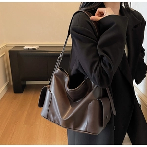 Detail of deep brown PU leather tote bag featuring side flap pockets and adjustable strap