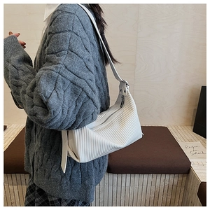 Close-up of white pleated dumpling bag worn by model over a grey knit cardigan