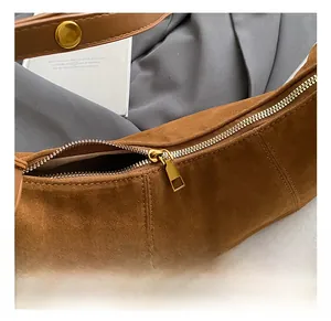 Gros plan du zip doré et des coutures sur un sac hobo en daim marron en forme de lune