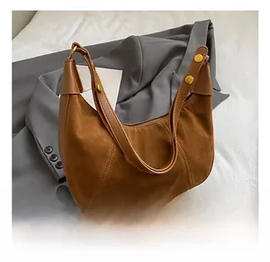 Gros plan du sac en daim marron avec bandoulière en cuir et rivets dorés