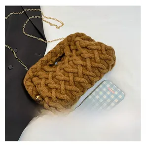 Détail de la maille tricotée et chaîne dorée du sac à bandoulière tressé marron
