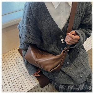 Detail of brown pleated faux leather crossbody bag with high-quality vertical texture