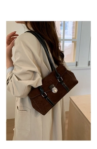 Detail of vintage baguette bag with brown suede texture and black leather straps