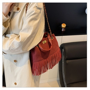 Gros plan du sac seau bordeaux matelassé avec de longues franges et un fermoir doré