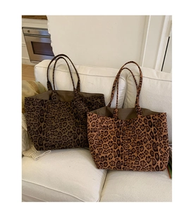 Détail de grands sacs cabas léopard en marron foncé et clair sur un canapé blanc