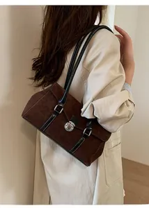 Close-up of brown suede hobo bag with black leather strap and silver twist-lock closure