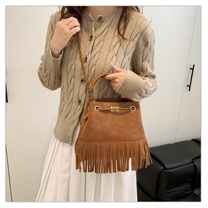 Détail d'un sac à bandoulière en daim marron avec pompons et chaîne en métal doré