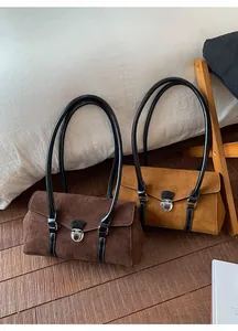 Close-up of suede shoulder bags in brown and mustard yellow with silver metal clasp
