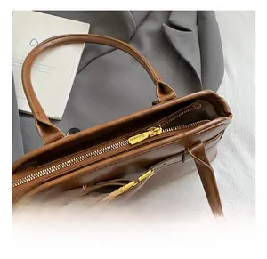 Dettaglio della borsa tote in pelle opaca marrone caramello con zip dorata e fibbia sobria