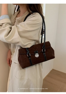 Detail of dark brown suede shoulder bag with black leather strap and silver clasp