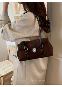 Detail showing brown suede baguette bag with black leather straps and silver buckle on model
