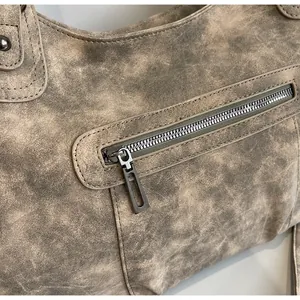 Detail of vintage tote bag showing textured leather surface and smooth metal zipper
