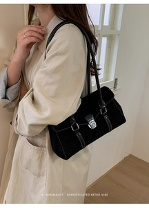Detail of minimalist black baguette bag with silver metallic buckle on a vintage strap